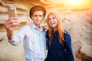 Çekici bir adam güzel bir kadın ile sarılma ve gülümseyerek. Onlar kum ocağı arka plan üzerinde selfie yapıyoruz.