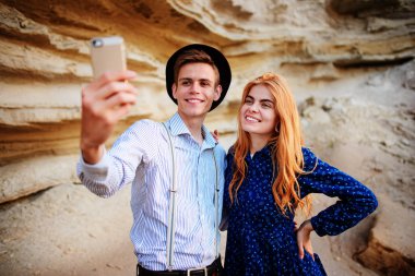 Çekici bir adam güzel bir kadın ile sarılma ve gülümseyerek. Onlar kum ocağı arka plan üzerinde selfie yapıyoruz.