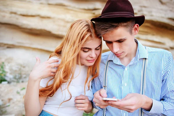 Çekici bir adam ve güzel kadın bir akıllı telefon ekranında bir kum ocağı arka plan üzerinde arıyoruz.