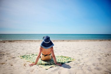 Genç kadın bir mavi şapka rahatlatıcı, tropikal plaj.