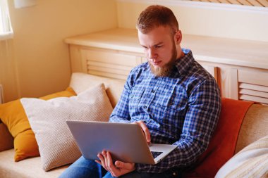 dizüstü bilgisayarınızda evde absorbe çalışan genç adam.