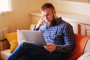 dizüstü bilgisayarınızda evde absorbe çalışan genç adam.