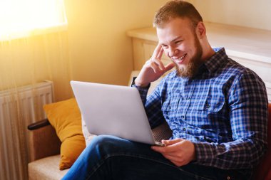 dizüstü bilgisayarınızda evde absorbe çalışan genç adam.