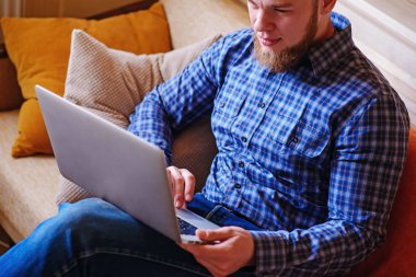 Genç adam sahilde bilgisayarla çalışma. Yakışıklı adam kanepede plajda döşeme dizüstü bilgisayar ile çalışma.