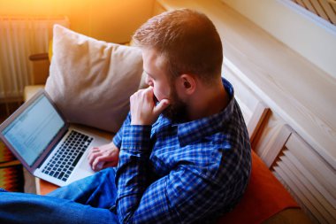 Genç adam sahilde bilgisayarla çalışma. Yakışıklı adam kanepede plajda döşeme dizüstü bilgisayar ile çalışma.