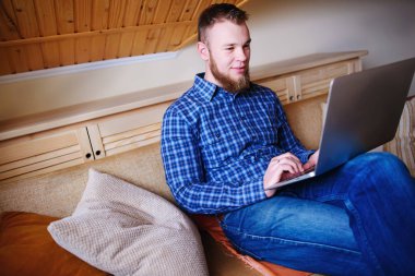 dizüstü bilgisayarınızda evde absorbe çalışan genç adam.