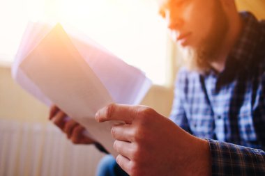 Genç yakışıklı adam kanepede oturan ve bir çalışma kağıdı saatler.