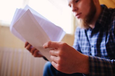 Genç yakışıklı adam kanepede oturan ve bir çalışma kağıdı saatler.