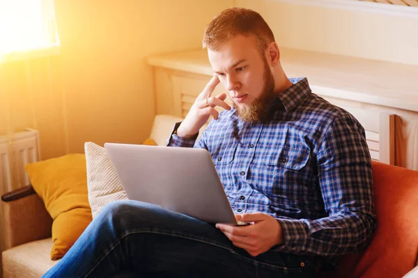 dizüstü bilgisayarınızda evde absorbe çalışan genç adam.