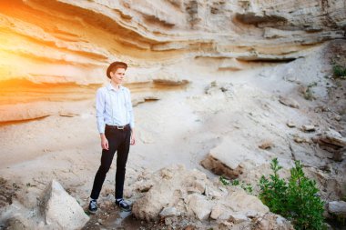 Çekici bir adam bir kum ocağı ortasında duran ve düşünceli mesafe seyir.