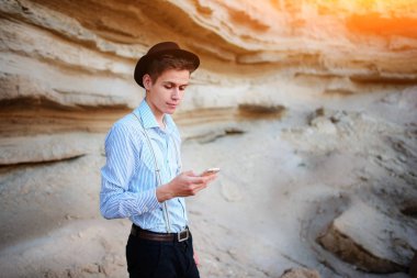 Bir akıllı telefon ekranına bir kum ocağı özgeçmişlerine bakarak çekici bir adam.