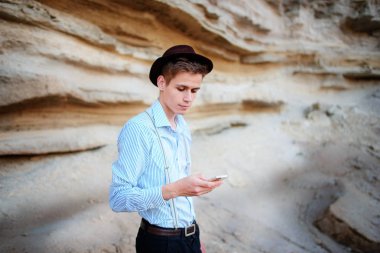 Bir akıllı telefon ekranına bir kum ocağı özgeçmişlerine bakarak çekici bir adam.