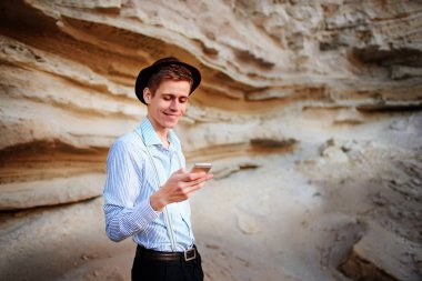 Bir akıllı telefon ekranına bir kum ocağı özgeçmişlerine bakarak çekici bir adam.