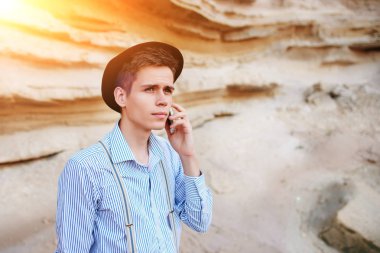 Çekici bir adam bir kum ocağı ortasında duran ve bir akıllı telefon üzerinden arama yapma.