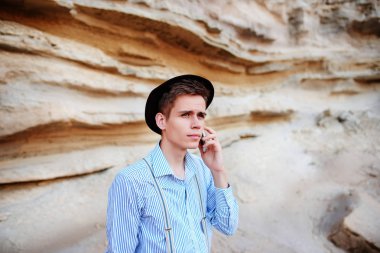 Çekici bir adam bir kum ocağı ortasında duran ve bir akıllı telefon üzerinden arama yapma.