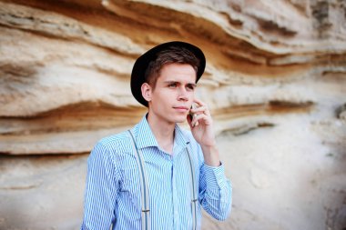 Çekici bir adam bir kum ocağı ortasında duran ve bir akıllı telefon üzerinden arama yapma.