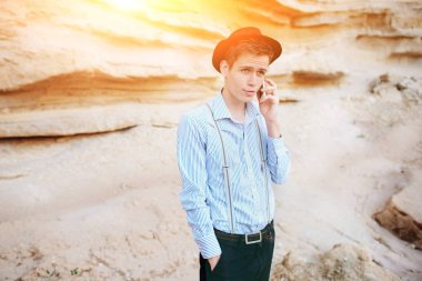 Çekici bir adam bir kum ocağı ortasında duran ve bir akıllı telefon üzerinden arama yapma.