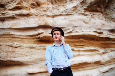 Çekici bir adam bir kum ocağı ortasında duran ve bir akıllı telefon üzerinden arama yapma.