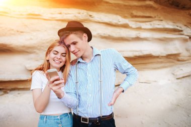 Çekici bir adam ve güzel kadın bir akıllı telefon ekranında bir kum ocağı arka plan üzerinde arıyoruz.