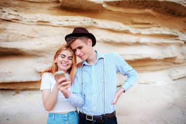 Çekici bir adam ve güzel kadın bir akıllı telefon ekranında bir kum ocağı arka plan üzerinde arıyoruz.