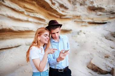 Çekici bir adam ve güzel kadın bir akıllı telefon ekranında bir kum ocağı arka plan üzerinde arıyoruz.