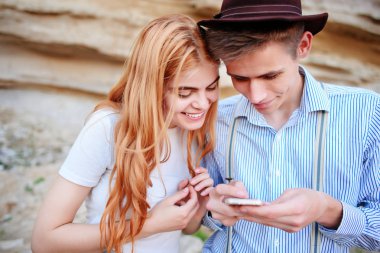 Çekici bir adam ve güzel kadın bir akıllı telefon ekranında bir kum ocağı arka plan üzerinde arıyoruz.