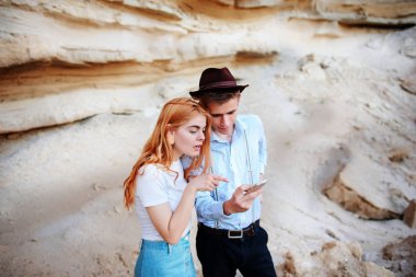 Çekici bir adam ve güzel kadın bir akıllı telefon ekranında bir kum ocağı arka plan üzerinde arıyoruz.