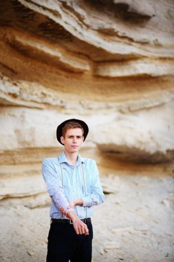 Şık çekici adam bir kum ocağı ortasında duruyor ve kameraya poz veriyor.