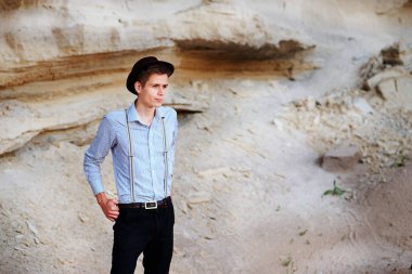 Şık çekici adam bir kum ocağı ortasında duruyor ve kameraya poz veriyor.