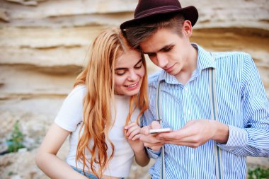 Çekici bir adam ve güzel kadın bir akıllı telefon ekranında bir kum ocağı arka plan üzerinde arıyoruz.