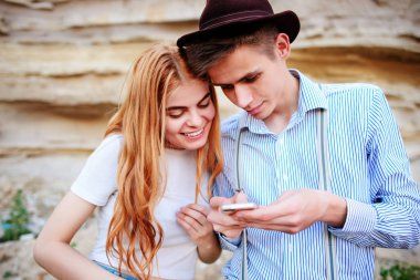 Çekici bir adam ve güzel kadın bir akıllı telefon ekranında bir kum ocağı arka plan üzerinde arıyoruz.