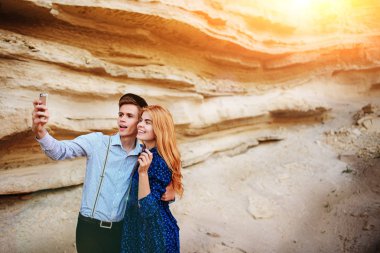 Çekici bir adam güzel bir kadın ile sarılma ve gülümseyerek. Onlar kum ocağı arka plan üzerinde selfie yapıyoruz.