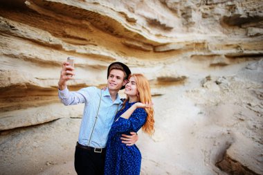 Çekici bir adam güzel bir kadın ile sarılma ve gülümseyerek. Onlar kum ocağı arka plan üzerinde selfie yapıyoruz.