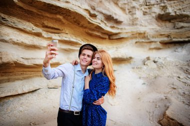 Çekici bir adam güzel bir kadın ile sarılma ve gülümseyerek. Onlar kum ocağı arka plan üzerinde selfie yapıyoruz.