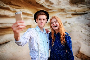 Çekici bir adam güzel bir kadın ile sarılma ve gülümseyerek. Onlar kum ocağı arka plan üzerinde selfie yapıyoruz.