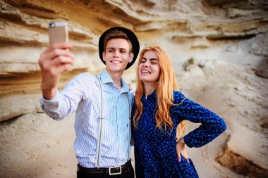 Çekici bir adam güzel bir kadın ile sarılma ve gülümseyerek. Onlar kum ocağı arka plan üzerinde selfie yapıyoruz.