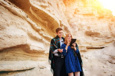 Güzel kadın ve yakışıklı bir battaniyeye sarılmış. Onlar gülümseyen ve bir tablet ekranında bir kum ocağı arka plan üzerinde seyir.