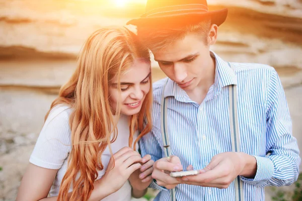 Çekici bir adam ve güzel kadın bir akıllı telefon ekranında bir kum ocağı arka plan üzerinde arıyoruz.