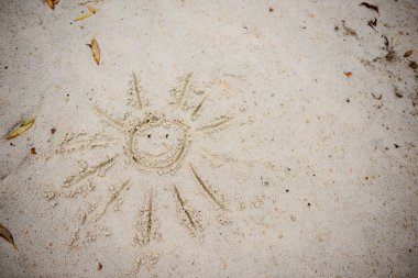 Bulutlu bir sonbahar gününde kuma çizilmiş güneş sembolü
