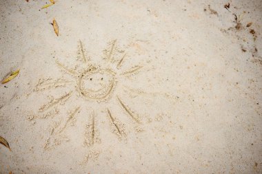 Bulutlu bir sonbahar gününde kuma çizilmiş güneş sembolü