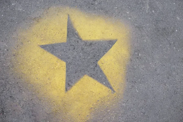 the yellow star is painted on gray asphalt.