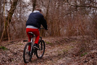 dağ yolu ormandaki bisiklet sürme sırt çantası ile genç adam.
