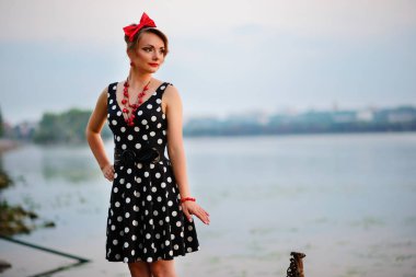 Gün batımını arka plan üzerinde göl kenarında duran giymiş kadın çok güzel genç.