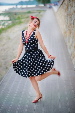 Elbiseli bir kız mutlu bir şekilde dışarıdan dans ediyor.