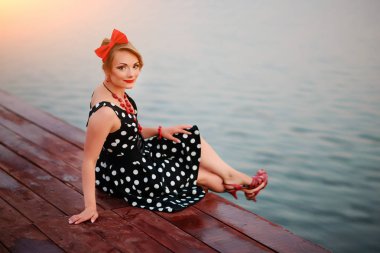 İskelede oturup güzel bir genç kadın giyinmiş.