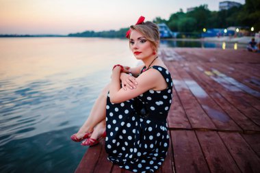 İskelede oturup güzel bir genç kadın giyinmiş.