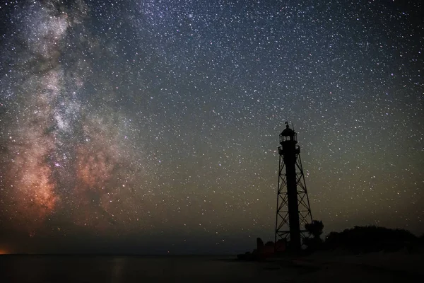 Silhouettes of the Old Lighthouse sandy beach and ocean against the background of the starry sky.