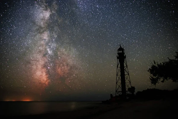 Silhouettes of the Old Lighthouse sandy beach and ocean against the background of the starry sky.
