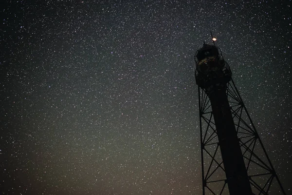 Silhouette of the Old Lighthouse against the background of the starry sky.