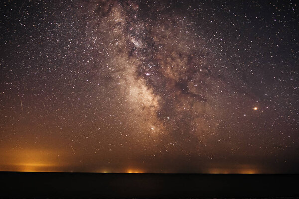 Фон яркого ночного звездного неба с Млечным Путем на нем и светом над водой
.